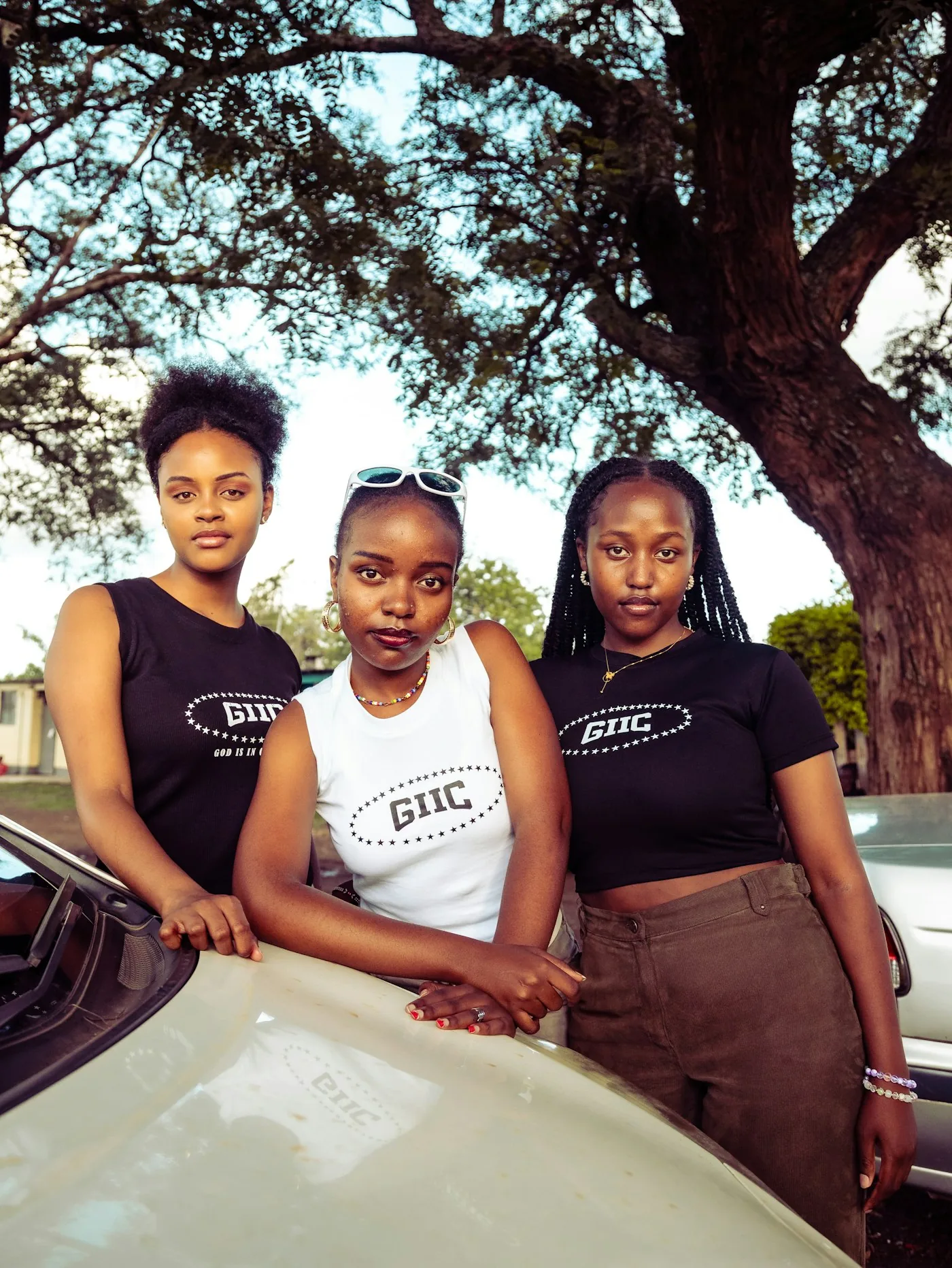 Three young women standing together outdoors in afternoon light